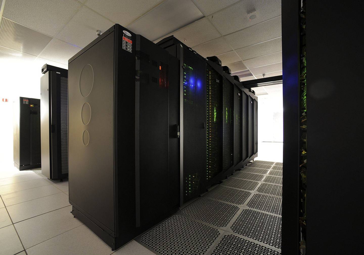 Rows of supercomputer racks with cable management in a machine room